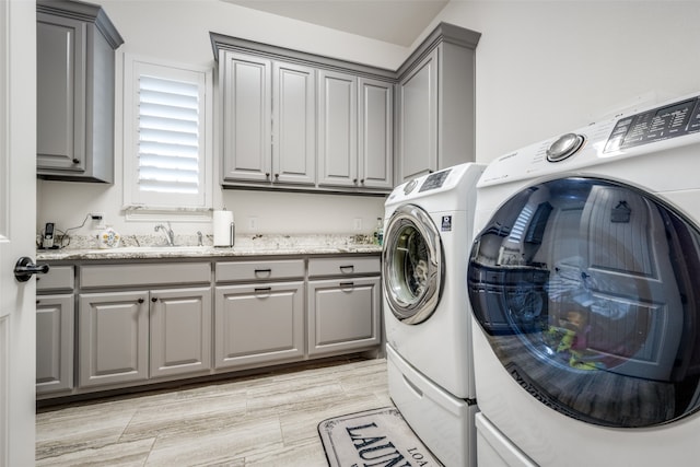 laundry area featuring washer and dryer, light hardwood / wood-style floors, cabinets, and sink