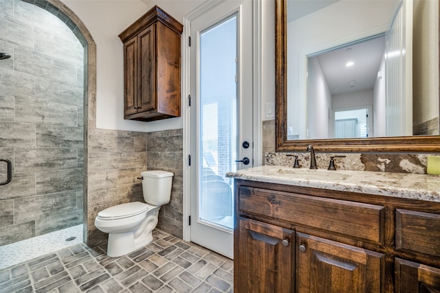 bathroom with walk in shower, vanity, toilet, and tile walls