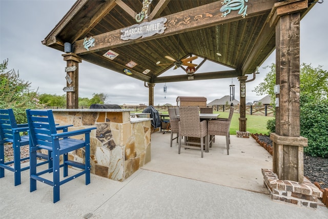 view of patio / terrace with a gazebo, ceiling fan, a bar, and exterior kitchen