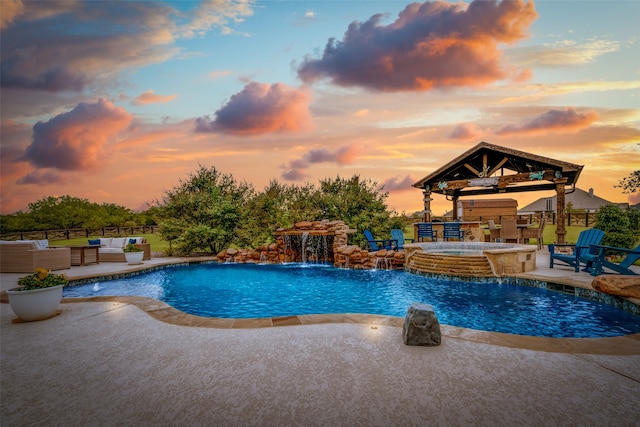 pool at dusk with a gazebo, pool water feature, a patio, and an in ground hot tub