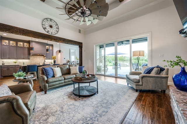 living room featuring ceiling fan, ornamental molding, a high ceiling, and light hardwood / wood-style flooring