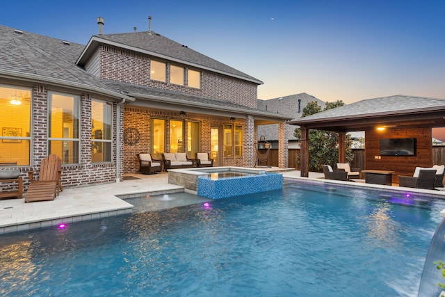 pool at dusk with a gazebo, a patio area, and an outdoor living space with a fireplace