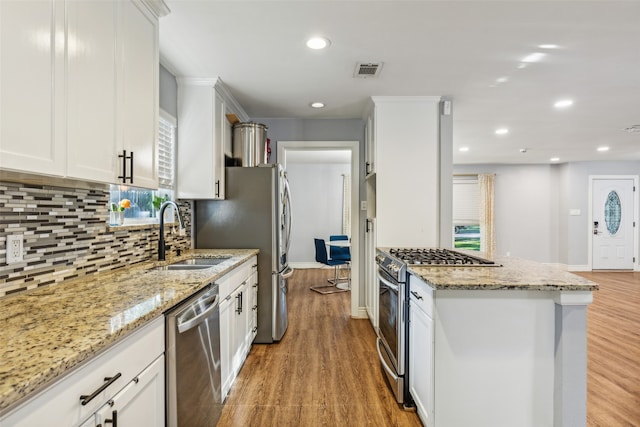 kitchen with light stone counters, stainless steel appliances, sink, light hardwood / wood-style flooring, and white cabinetry