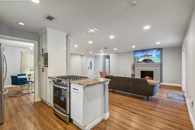 kitchen featuring light stone countertops, appliances with stainless steel finishes, light hardwood / wood-style flooring, and white cabinetry