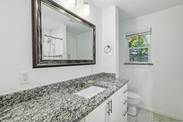 bathroom featuring a tile shower, vanity, and toilet