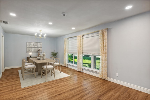 dining area with hardwood / wood-style floors and a notable chandelier