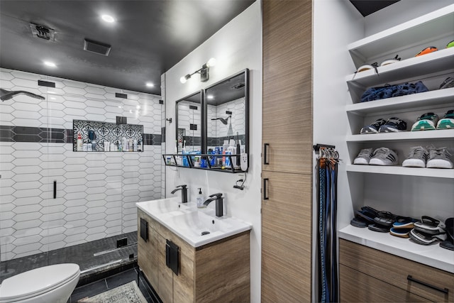 bathroom with tiled shower, tile patterned floors, vanity, and toilet