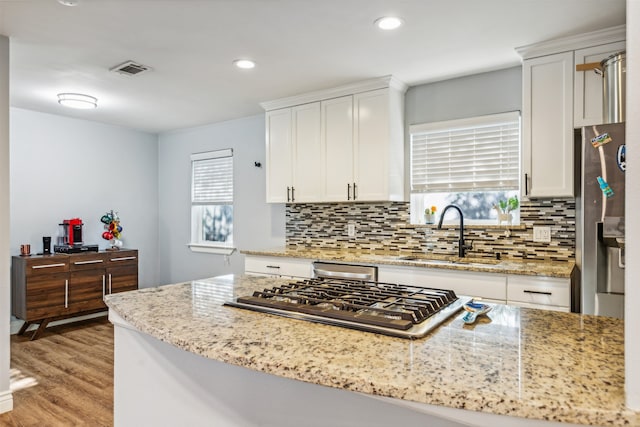 kitchen featuring light stone countertops, sink, white cabinets, and light hardwood / wood-style flooring