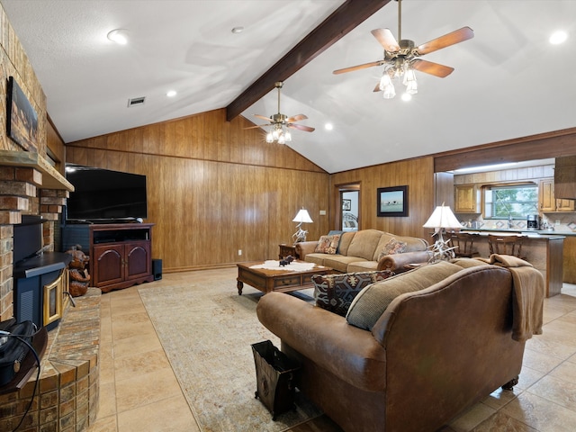 tiled living room featuring lofted ceiling with beams, wood walls, a wood stove, and ceiling fan