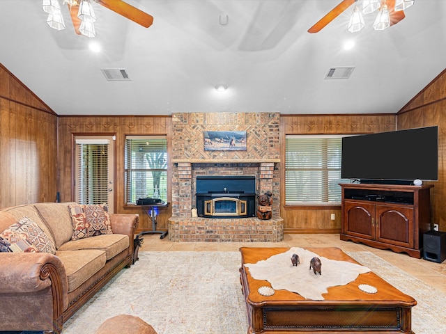 living room featuring wood walls, a fireplace, ceiling fan, and lofted ceiling