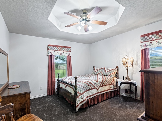 bedroom featuring ceiling fan, a textured ceiling, and dark colored carpet