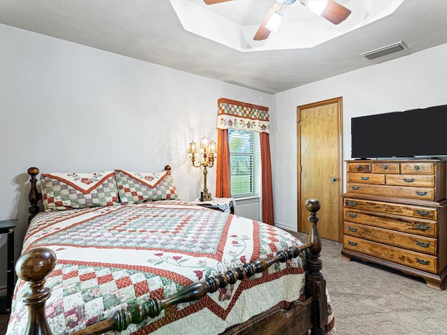 bedroom featuring ceiling fan, light colored carpet, and a textured ceiling