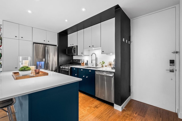 kitchen featuring appliances with stainless steel finishes, light hardwood / wood-style flooring, white cabinetry, and sink