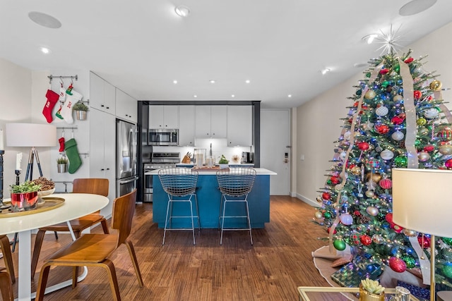 kitchen featuring a kitchen bar, appliances with stainless steel finishes, a kitchen island, dark wood-type flooring, and white cabinetry