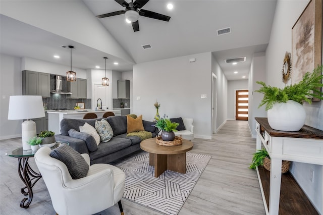 living room with light hardwood / wood-style floors, high vaulted ceiling, ceiling fan, and sink