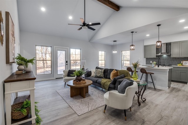 living room with beamed ceiling, light hardwood / wood-style floors, high vaulted ceiling, and ceiling fan