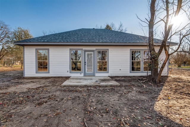 rear view of property featuring a patio area and a shingled roof