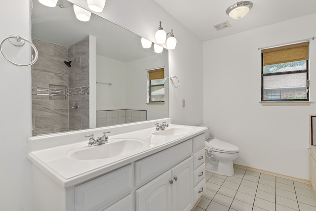 bathroom featuring a tile shower, tile patterned flooring, vanity, and toilet