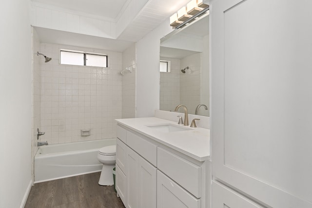 full bathroom with vanity, tiled shower / bath, crown molding, hardwood / wood-style flooring, and toilet