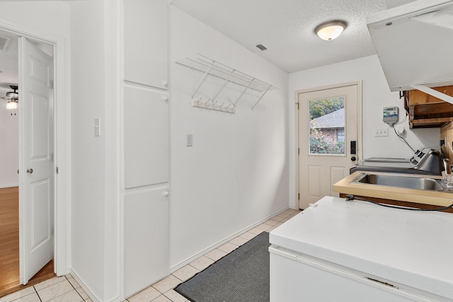 laundry room featuring sink, light tile patterned floors, and a textured ceiling