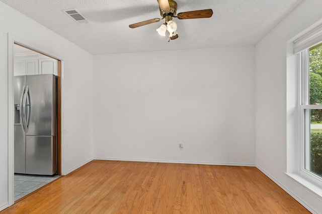 empty room with ceiling fan, a textured ceiling, and light hardwood / wood-style flooring