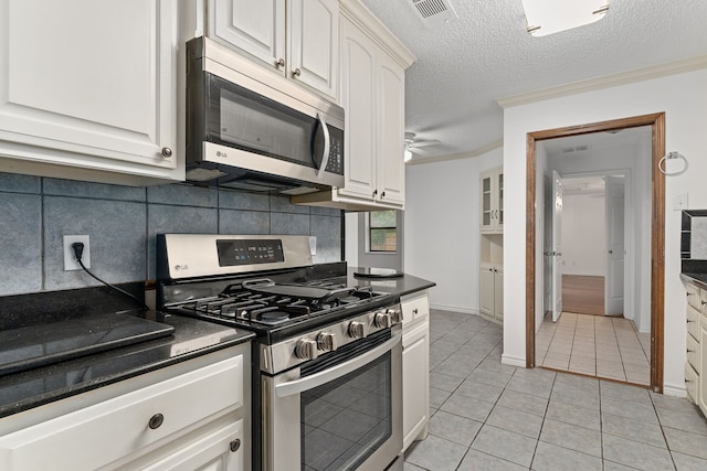 kitchen with appliances with stainless steel finishes, tasteful backsplash, a textured ceiling, white cabinets, and light tile patterned flooring