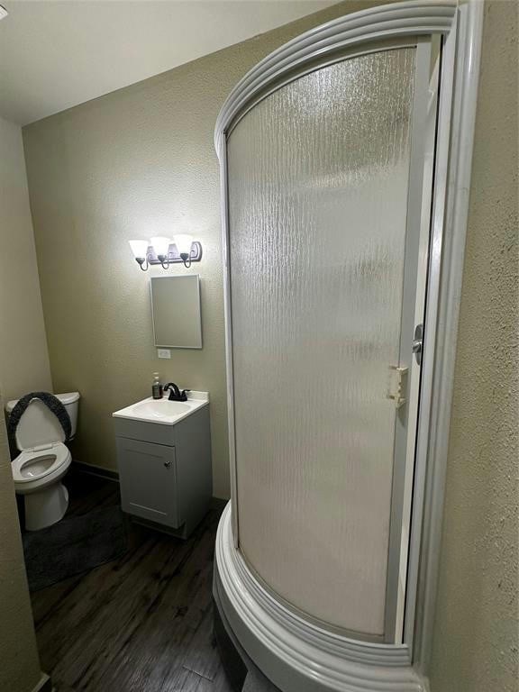 bathroom with walk in shower, vanity, toilet, and hardwood / wood-style floors