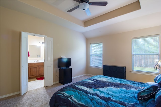 carpeted bedroom with ceiling fan, a raised ceiling, sink, and connected bathroom