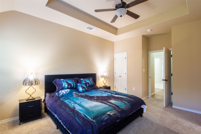 bedroom with ceiling fan, carpet floors, and a tray ceiling