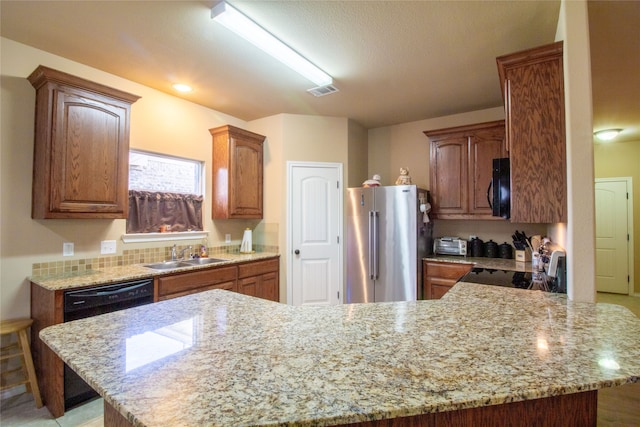 kitchen with kitchen peninsula, light stone counters, sink, and black appliances