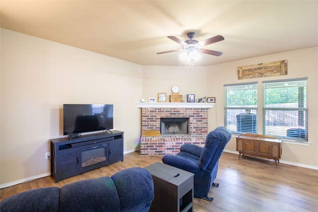 living room with a fireplace, light wood-type flooring, and ceiling fan