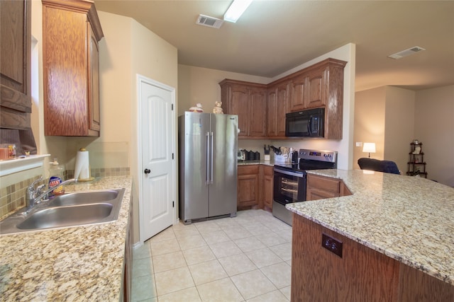 kitchen with light stone counters, sink, light tile patterned floors, and stainless steel appliances