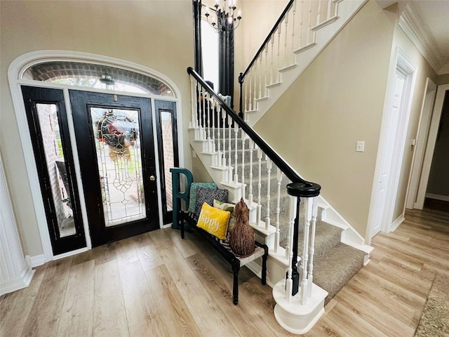 entrance foyer with hardwood / wood-style floors, ornamental molding, and a notable chandelier