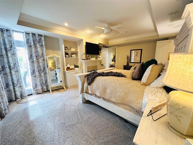 bedroom with ceiling fan, a raised ceiling, light wood-type flooring, and ornamental molding