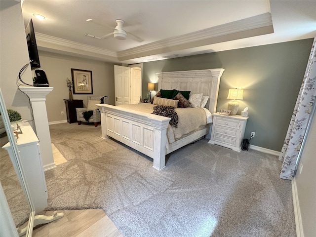 carpeted bedroom with a tray ceiling, ceiling fan, and crown molding