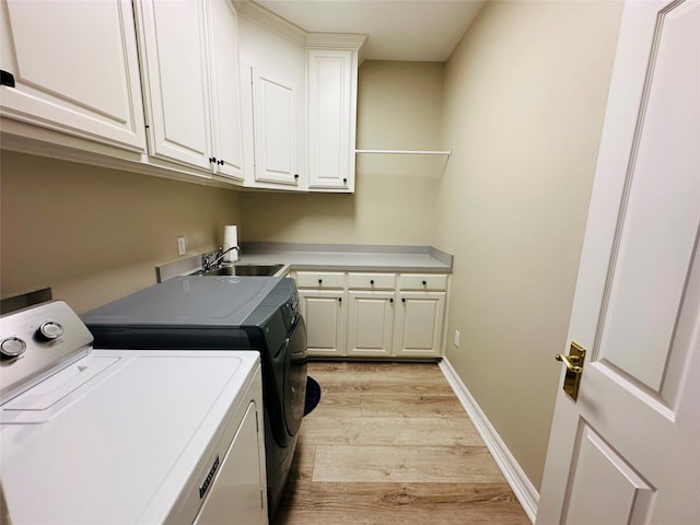 laundry room with cabinets, washing machine and dryer, light hardwood / wood-style flooring, and sink