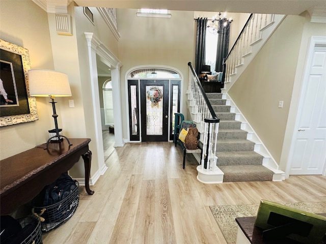 foyer entrance featuring a chandelier, ornamental molding, and light hardwood / wood-style flooring