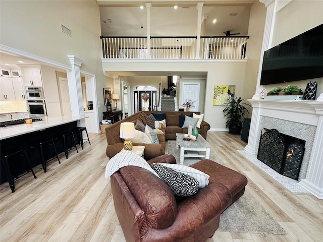 living room featuring a tile fireplace, light hardwood / wood-style floors, and ornate columns