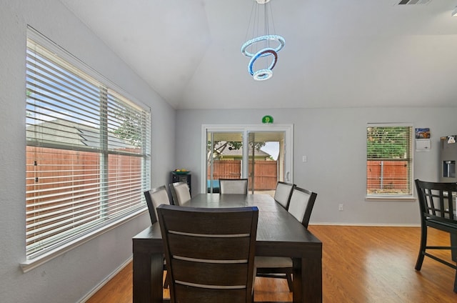 dining space with light wood-type flooring and vaulted ceiling