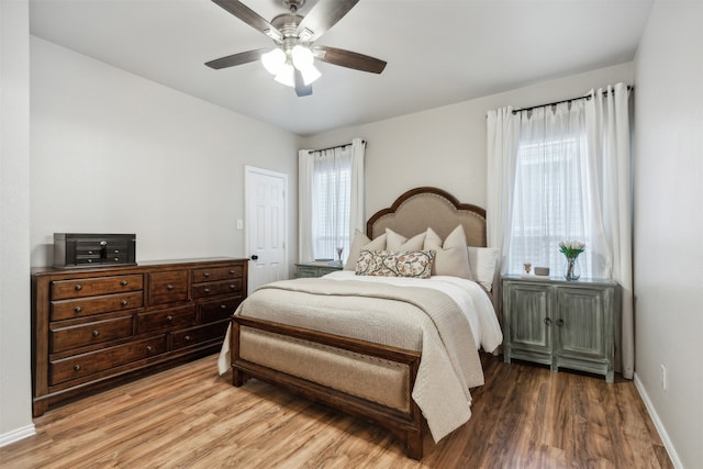 bedroom with hardwood / wood-style flooring, multiple windows, and ceiling fan