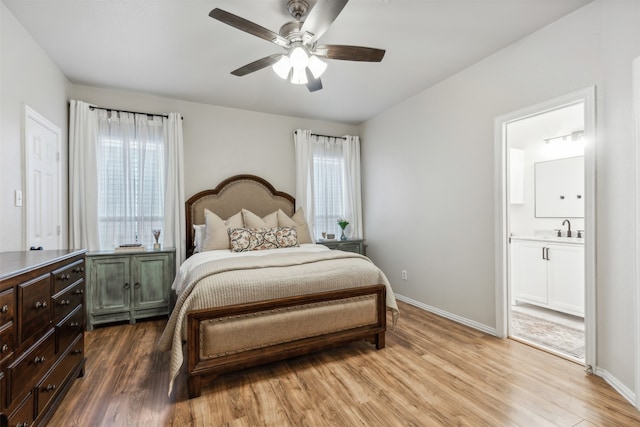 bedroom with ensuite bath, ceiling fan, sink, and light wood-type flooring