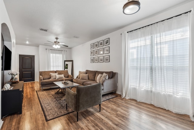 living room featuring wood-type flooring, plenty of natural light, and ceiling fan