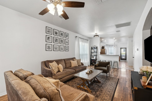 living room with ceiling fan and dark hardwood / wood-style flooring