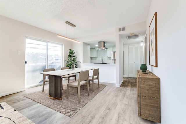 dining room featuring a textured ceiling, light wood-type flooring, and sink