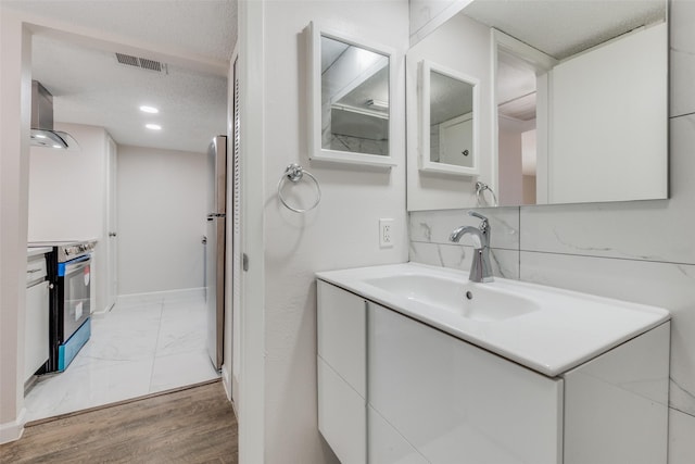 bathroom featuring wood-type flooring, a textured ceiling, vanity, and backsplash