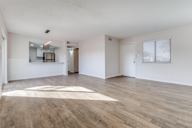 unfurnished living room with a textured ceiling and light wood-type flooring