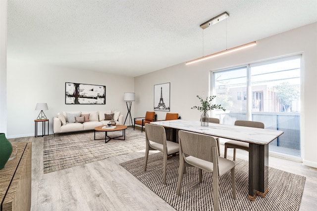 dining area with a textured ceiling and light hardwood / wood-style floors