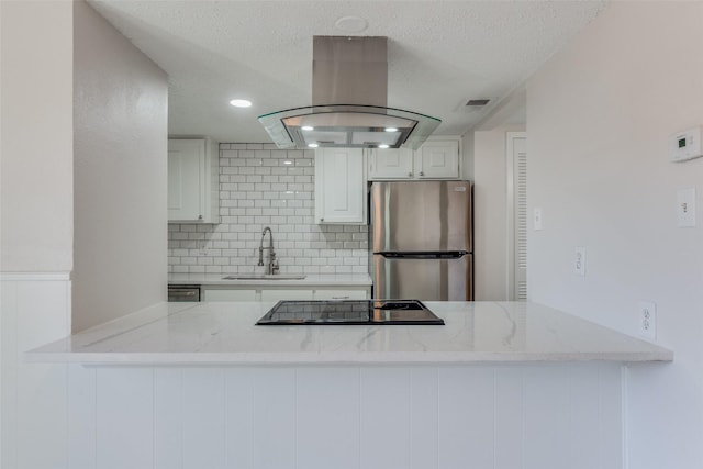 kitchen featuring white cabinets, sink, stainless steel fridge, island range hood, and kitchen peninsula