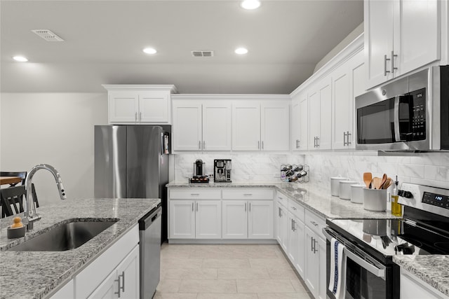 kitchen with light stone counters, white cabinetry, sink, and appliances with stainless steel finishes