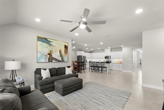 living room with ceiling fan, light tile patterned floors, and vaulted ceiling